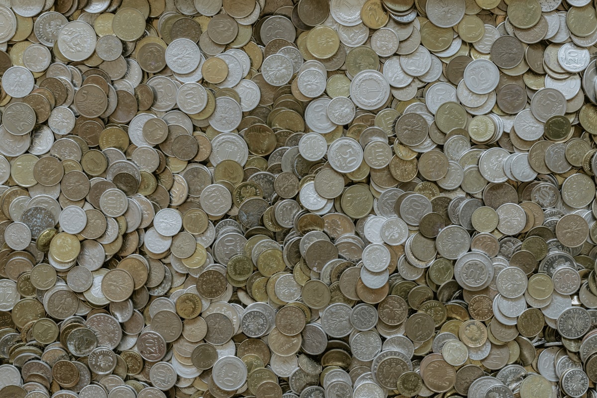 Savings jar filled with coins and dollar bills on a desk