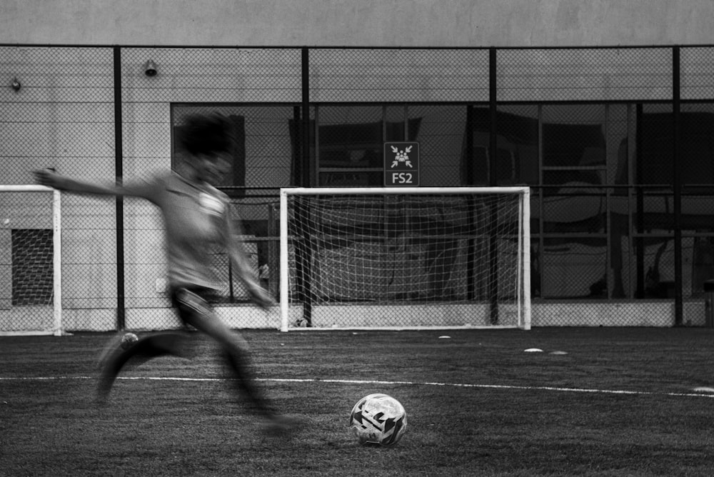 grayscale photography of person playing soccer ball