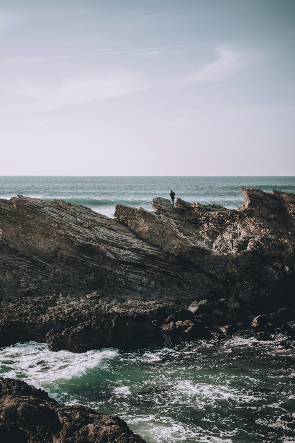 person standing on sea rock