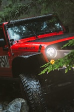 red Jeep Wrangler with rugged car tyres in an off road setting