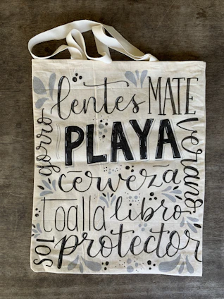 A white canvas tote bag featuring a delicate mandala design in black ink.