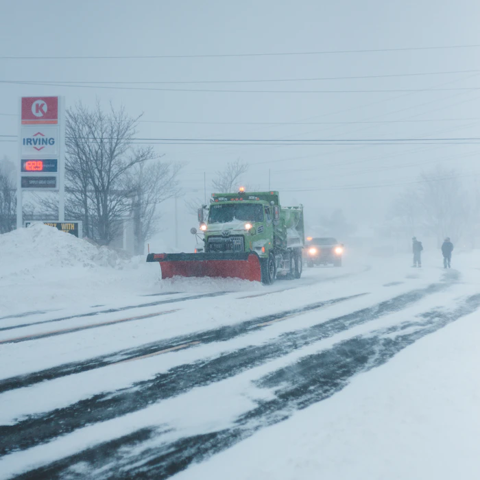 Truck with a plow blade clearing snow from a road