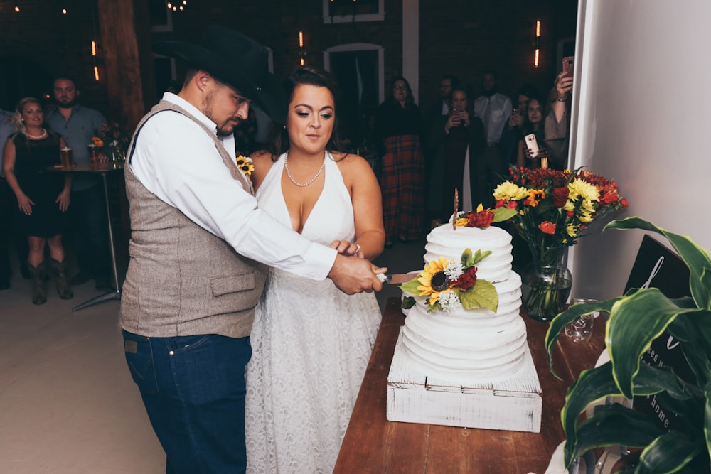 man and woman cutting 3-tier cake