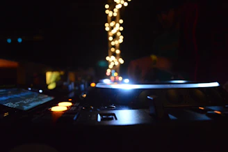 A joyful wedding DJ setting up his equipment with colorful lights glowing in the background.