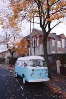 Black and white photo of a Volkswagen Type 2 bus surrounded by autumn leaves.