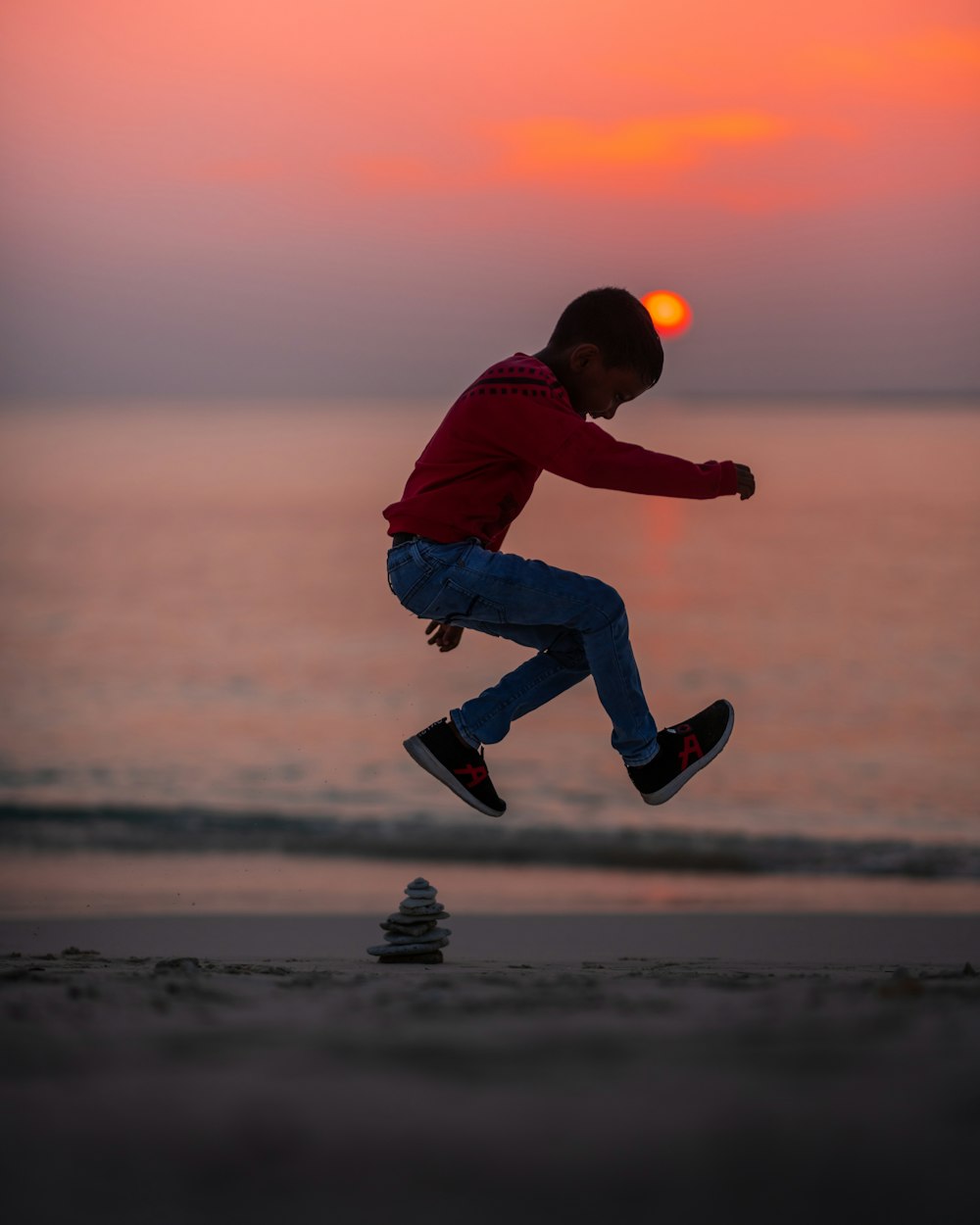 boy jumping on seashore during golden hour