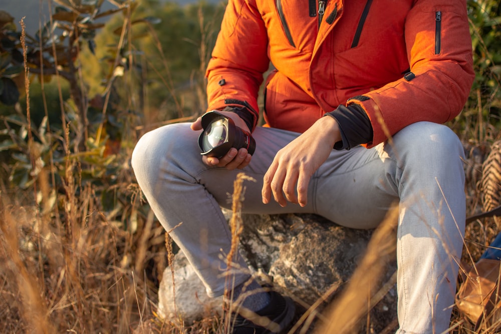 selective focus photography of sitting man holding zoom lens