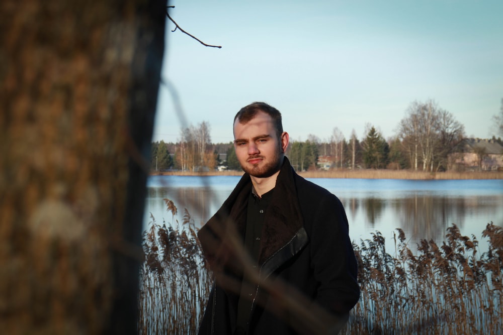 selective focus photography of standing man near outdoor next to body of water during daytime