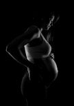 grayscale photo of pregnant woman near black surface