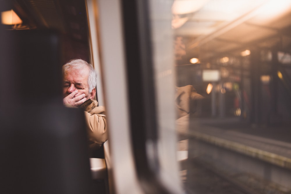 a man is sitting on a train and talking on a cell phone