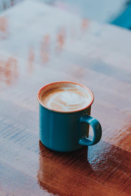 A cozy ceramic mug with a warm latte on a wooden table