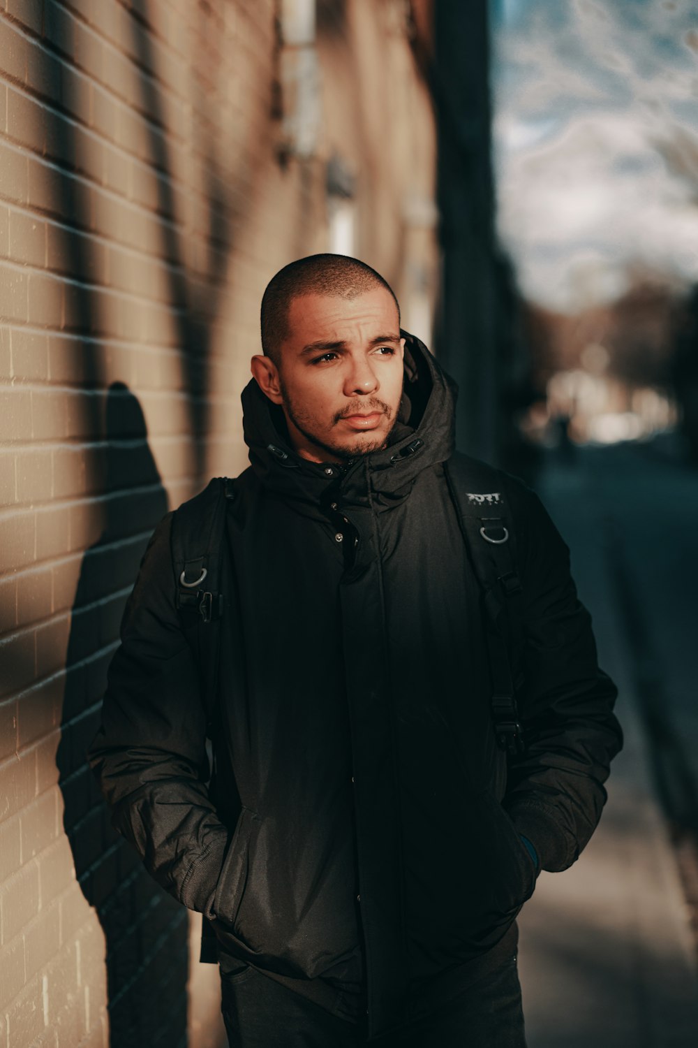 man in black jacket standing beside wall