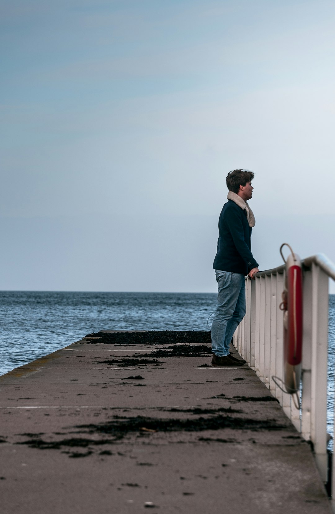 man in blue sweater standing beside rails