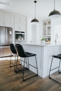 A contemporary kitchen island with bar stools and pendant lights.