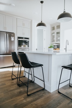 A contemporary kitchen island with bar stools and pendant lights.