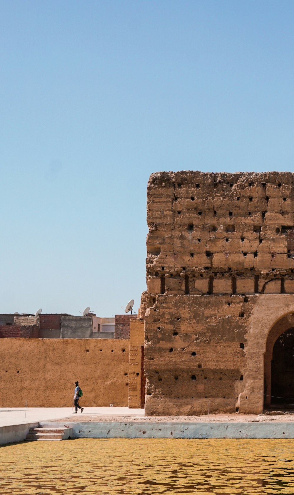 person walking beside wall during daytime