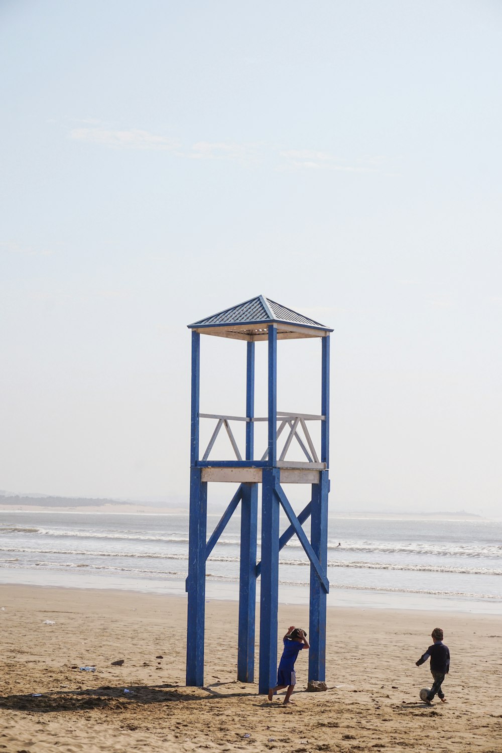 Dos personas caminando al lado de la torre en la playa