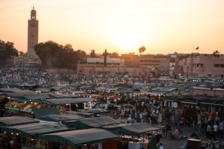 A warm sunset over Marrakech's medina with bustling streets and colorful market stalls.