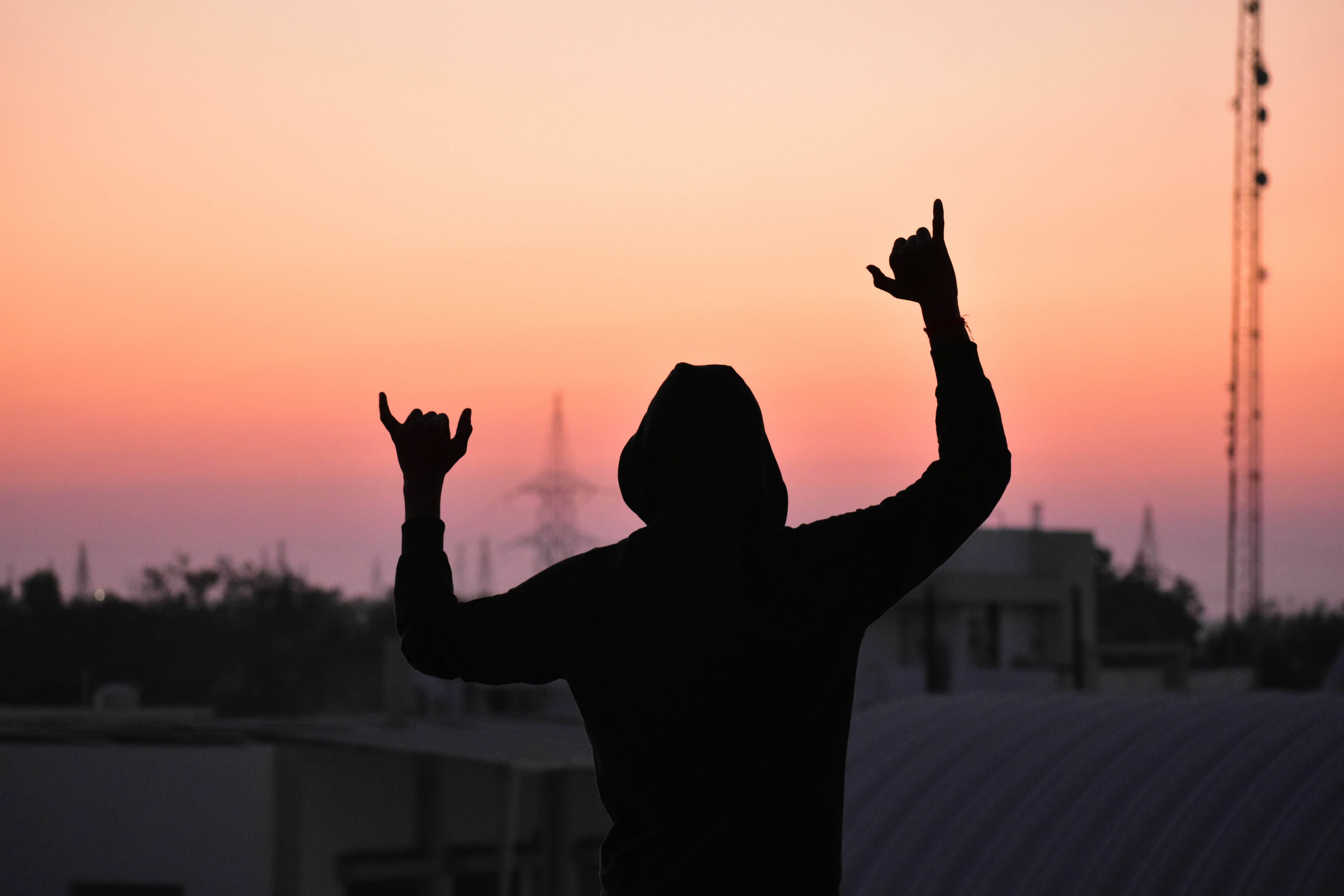 Silueta de la persona que levanta la mano durante la puesta del sol