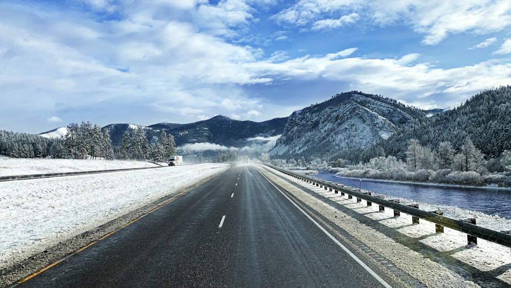 gray concrete road near mountain under white clouds during daytime