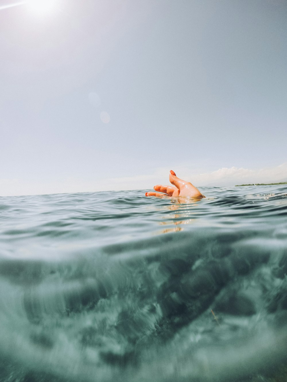 la mano de la persona en el cuerpo de agua durante el día