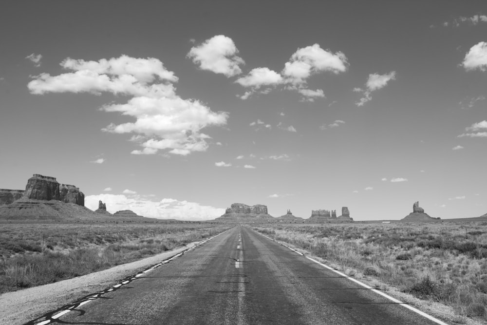 grayscale photo of road under cloudy sky