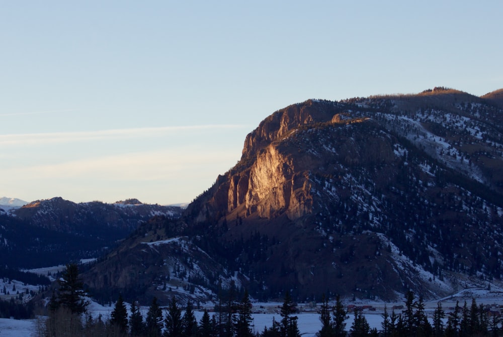 brown rocky mountain near body of water during daytime