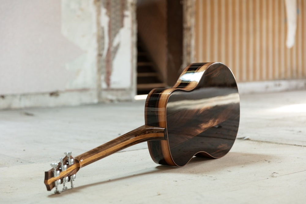 brown acoustic guitar on white floor