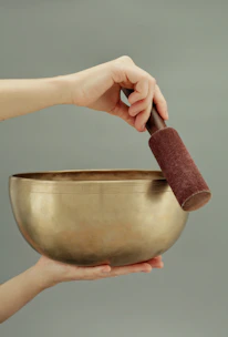 Hands gently holding a singing bowl with soft shadows around.