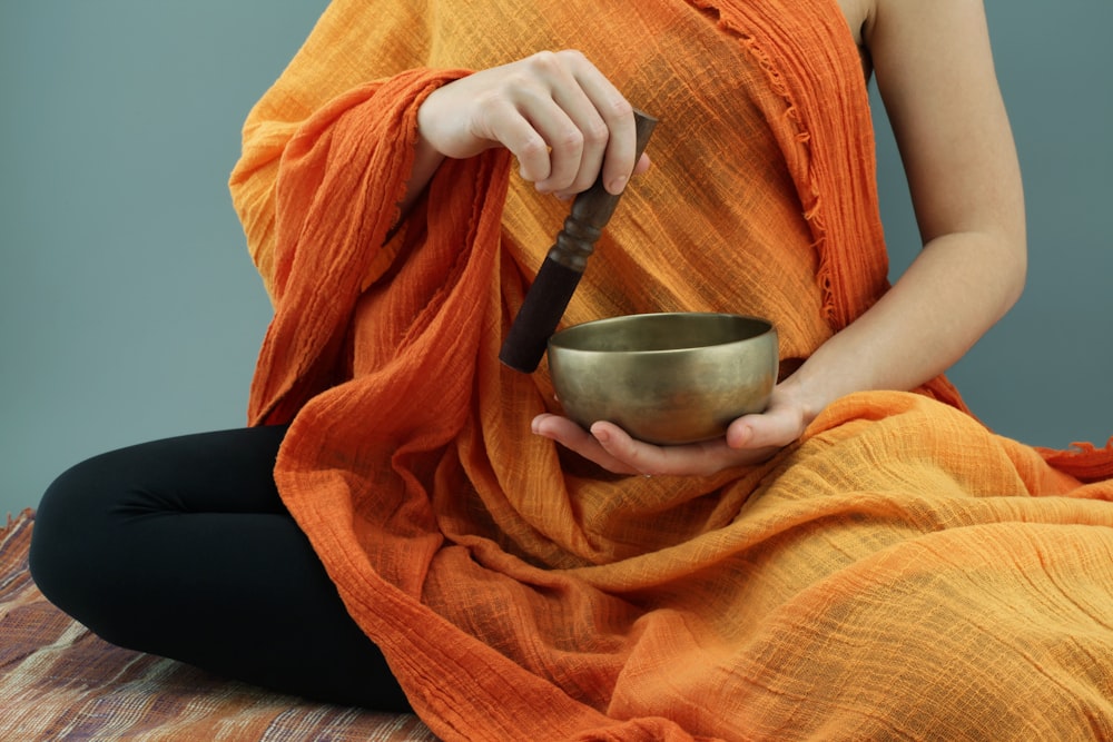 person in orange scarf holding silver round bowl