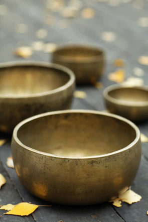 Tibetan singing bowls arranged on a wooden floor emitting gentle vibrations.