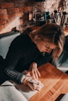 woman in black sweater writing on book