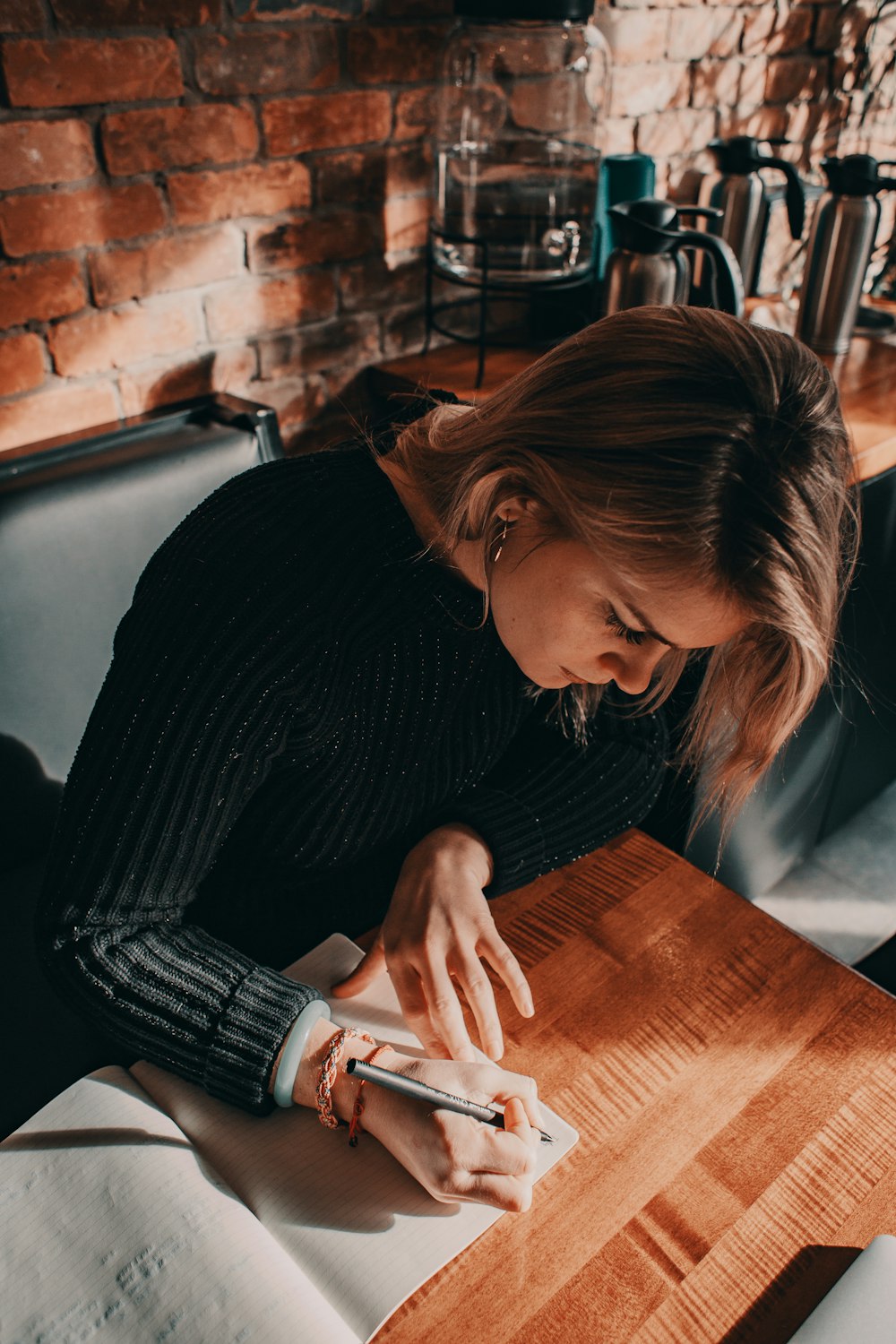 donna in maglione nero che scrive sul libro