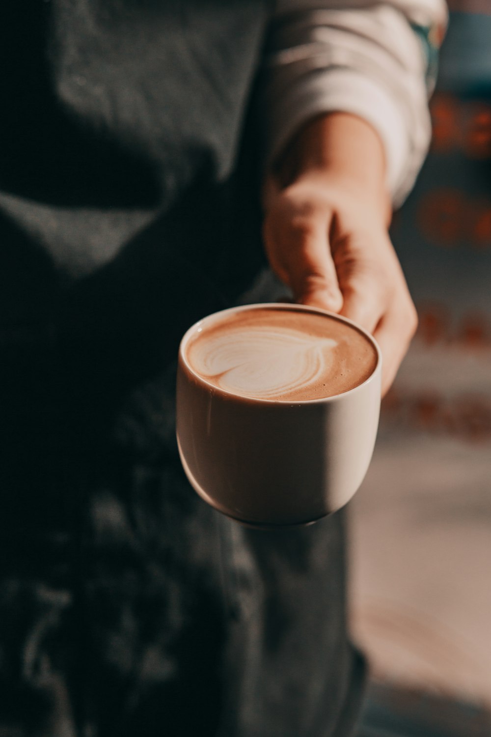 personne tenant une tasse de thé brune