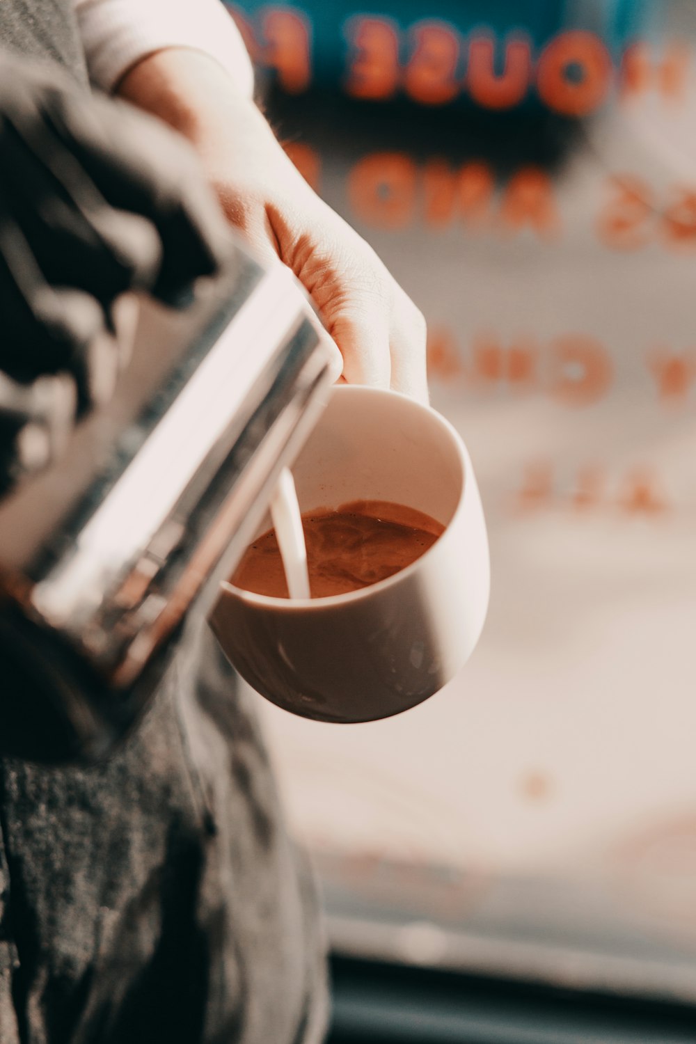 a person pouring a cup of coffee from a coffee maker