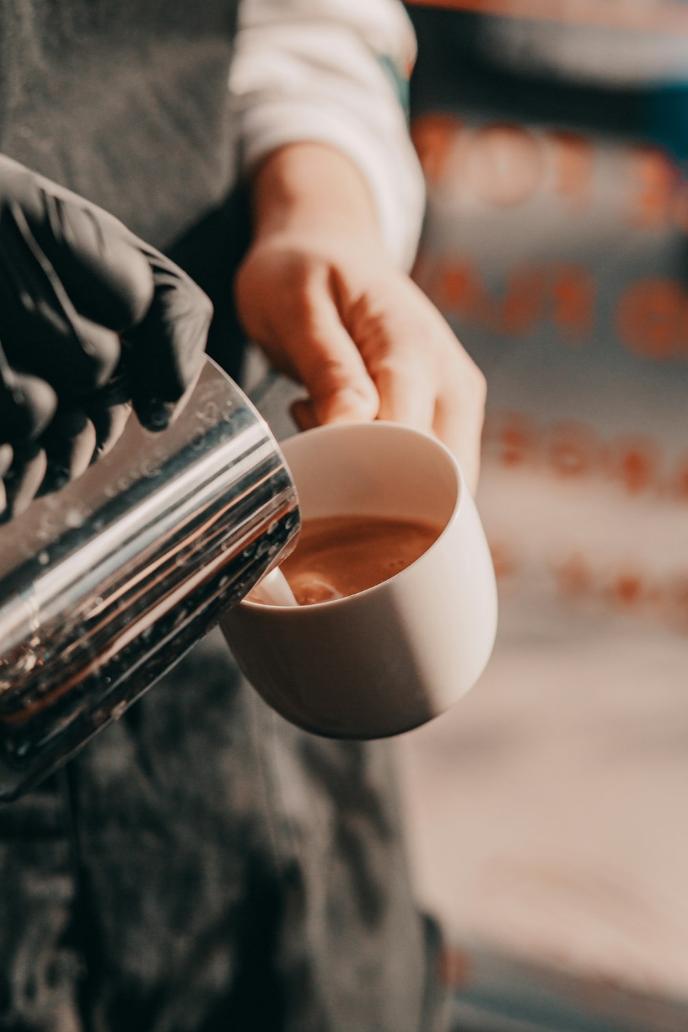 person pouring cream on white ceramic mug