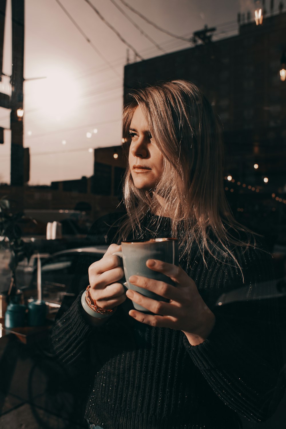 woman in black top holding cup of coffee
