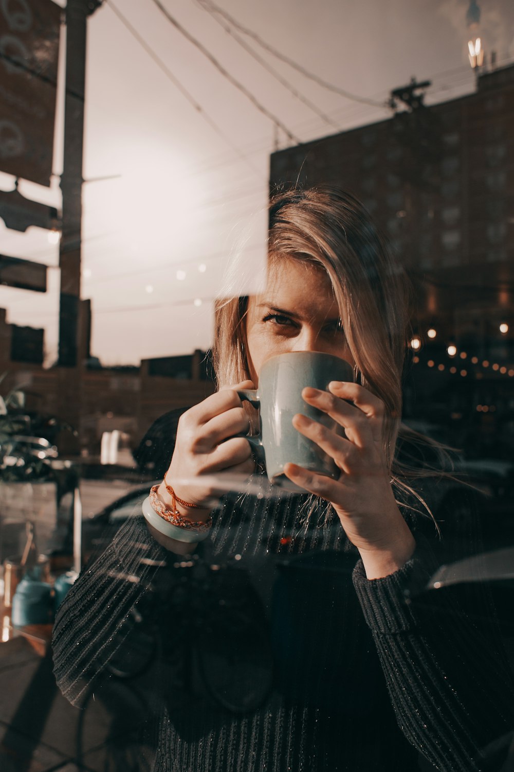 a woman holding a cup of coffee in front of a window