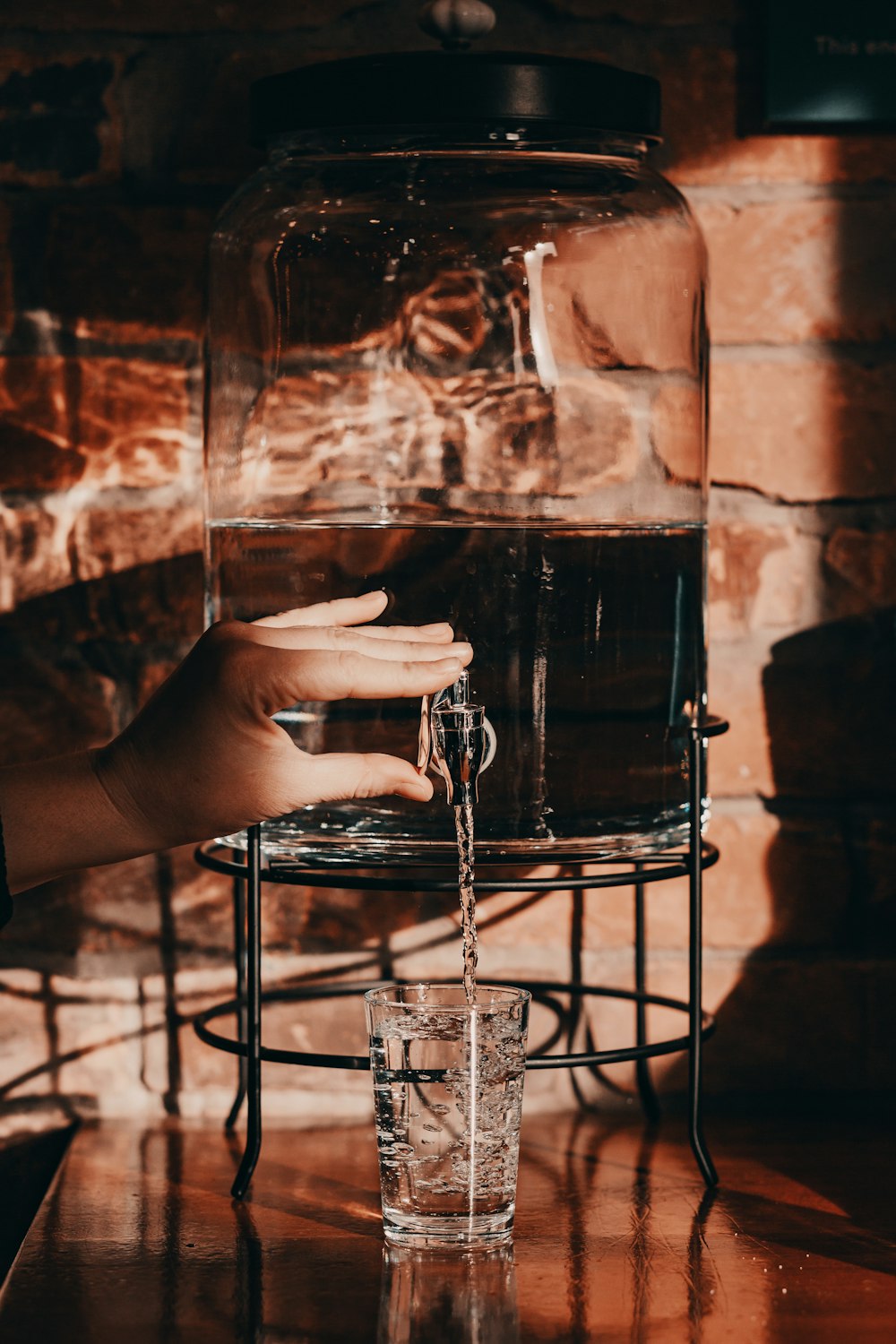 person pouring water on glass from jug