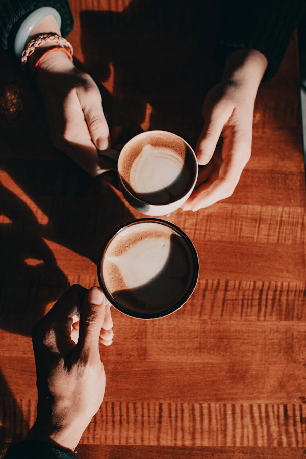 A person holding a phone next to a cup of coffee