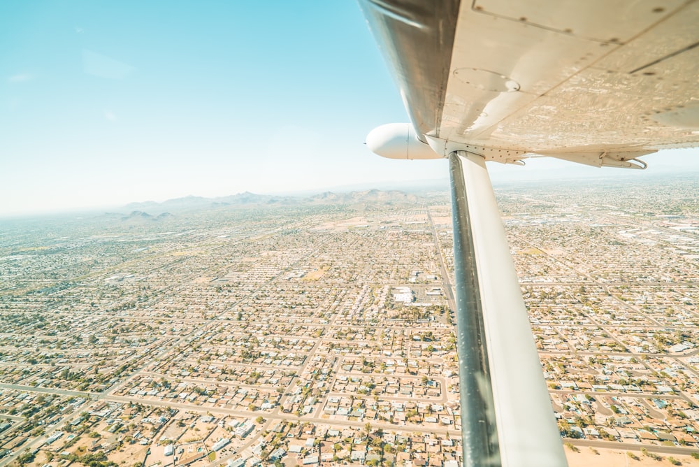 white airplane wing over city during daytime