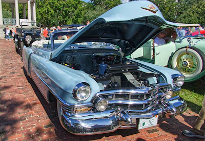 A beautifully restored antique car displayed at a sunny outdoor car show.