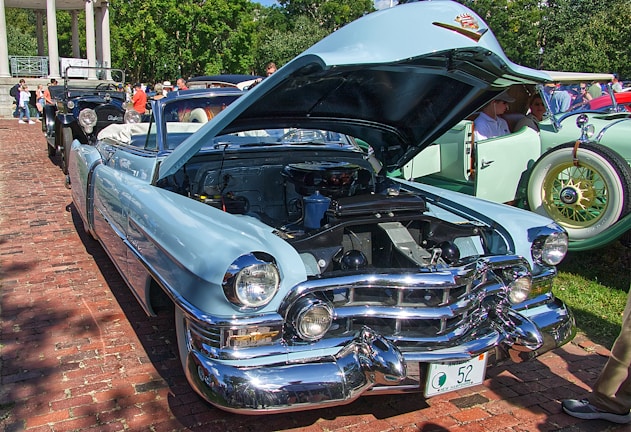 A classic vintage car displayed at an outdoor auto show with people admiring it.