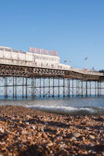 A bright, sunny view of Eastbourne pier with blue skies and gentle waves.