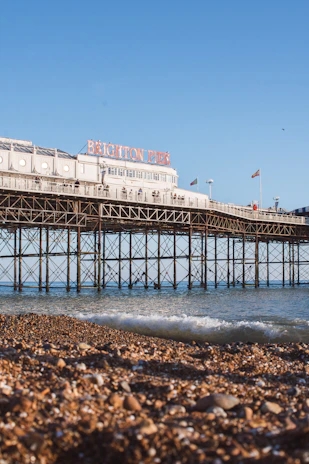 A bright, sunny view of Eastbourne pier with blue skies and gentle waves.