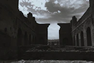 A dramatic black and white shot of ancient ruins under a stormy sky.