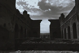 A dramatic black and white shot of ancient ruins under a stormy sky.