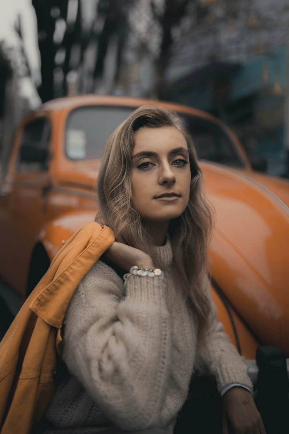 selective focus photography of woman next to yellow vehicle during daytime