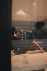 man and woman kissing beside table