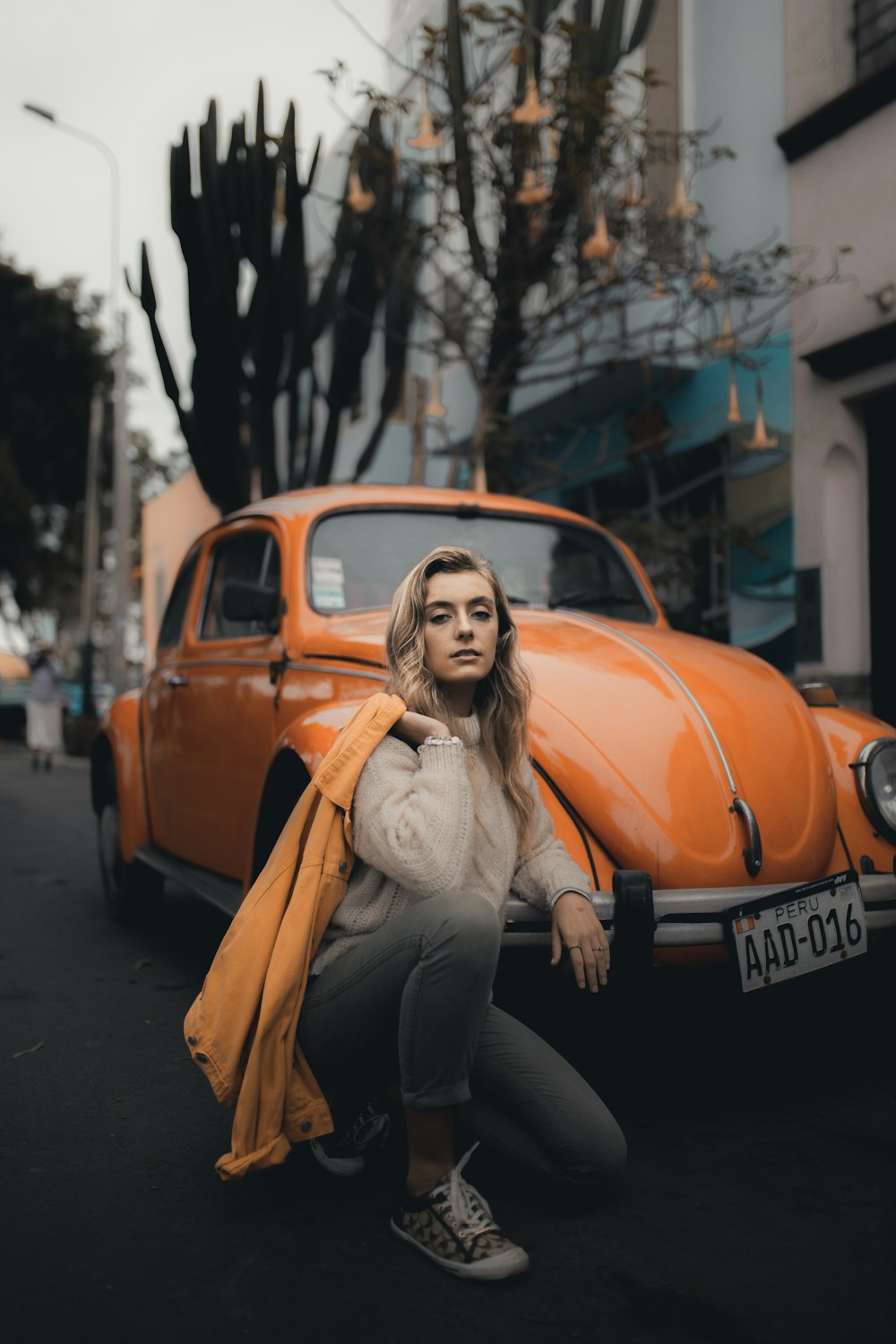 woman kneeling beside Volkswagen Beetle